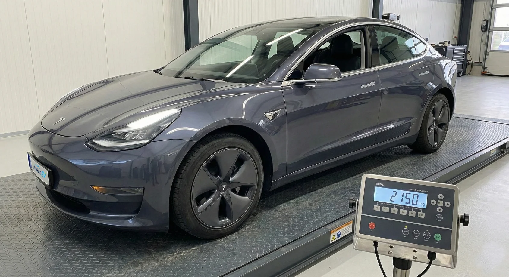 รถ Tesla บนเครื่องชั่งน้ำหนักแสดงตัวเลข 2150 kg